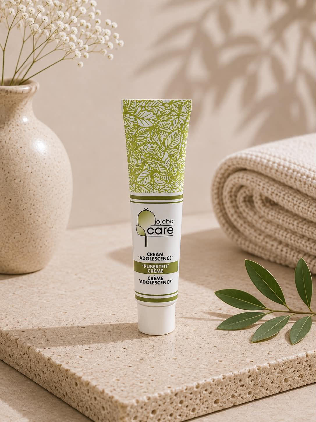 Tube de crème Jojoba Care pour l'adolescence sur un socle en pierre naturelle.